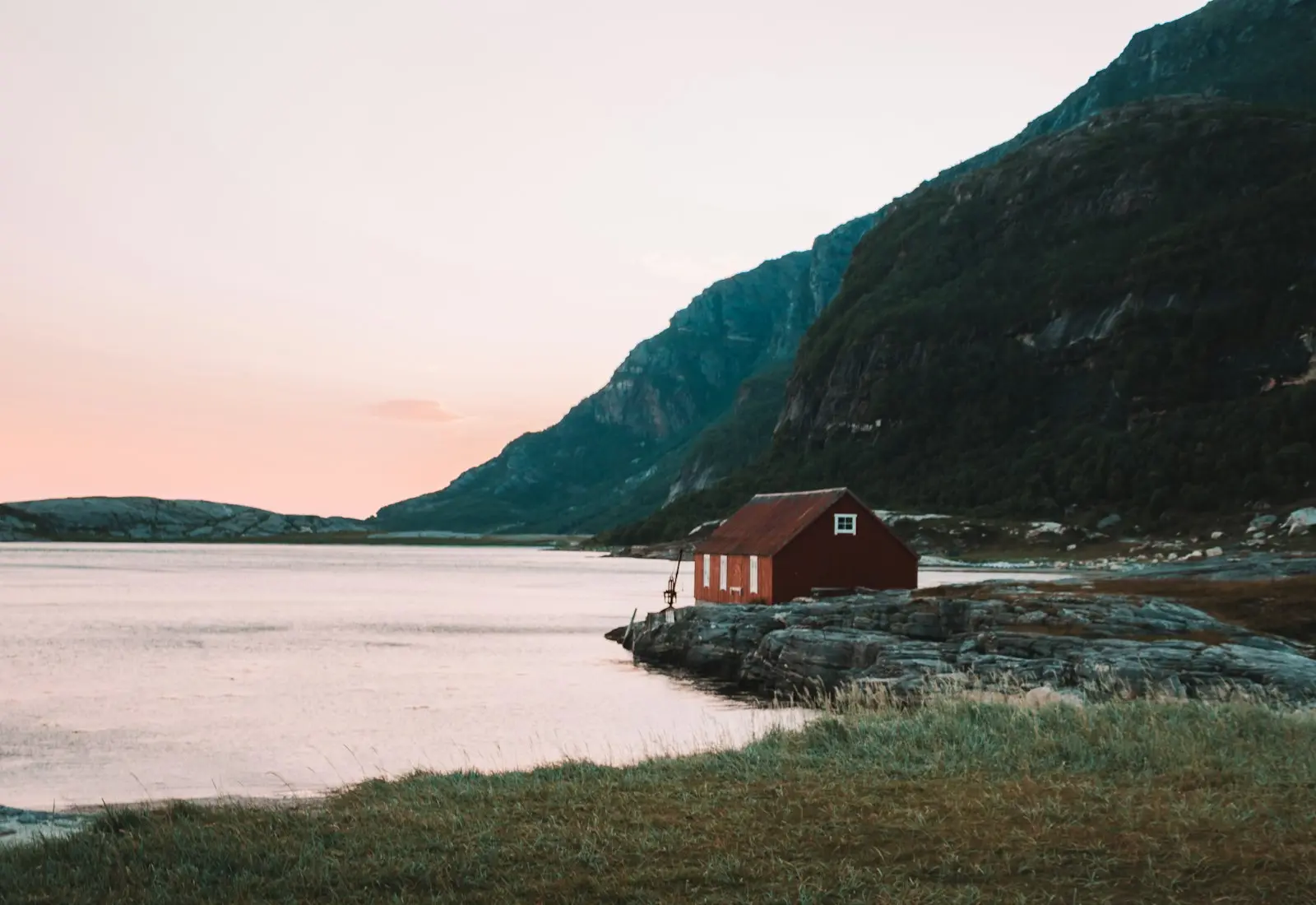 Enebolig ved fjord i kveldslys